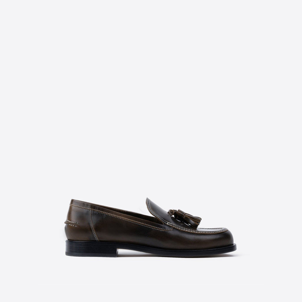 Brown leather loafer with tassel on a white background
