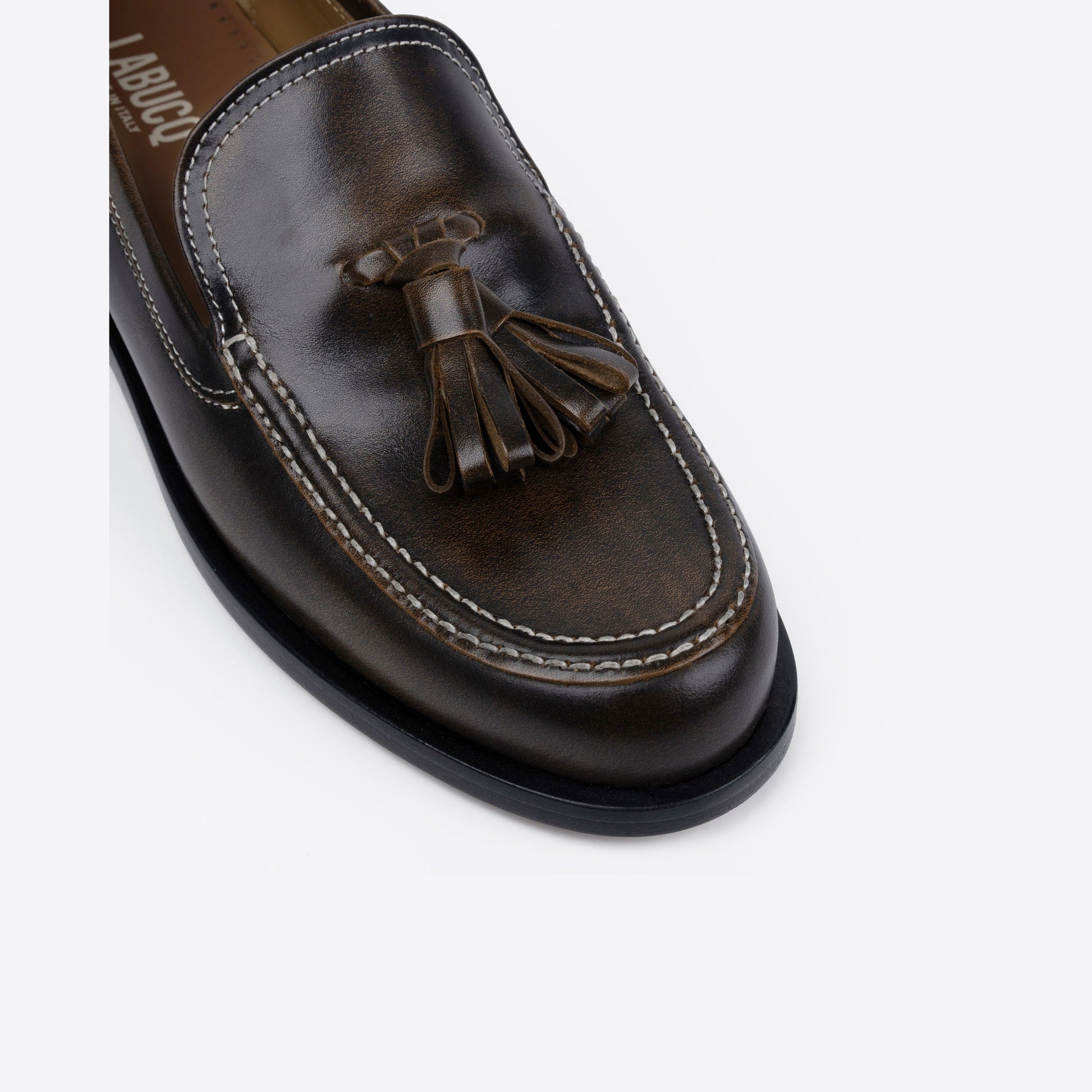 Brown leather loafer with tassel on a white background