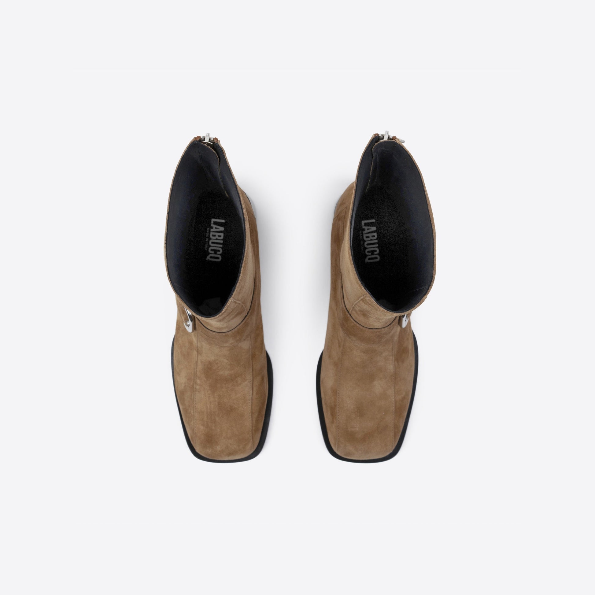 Pair of brown suede boots with black soles on a white background