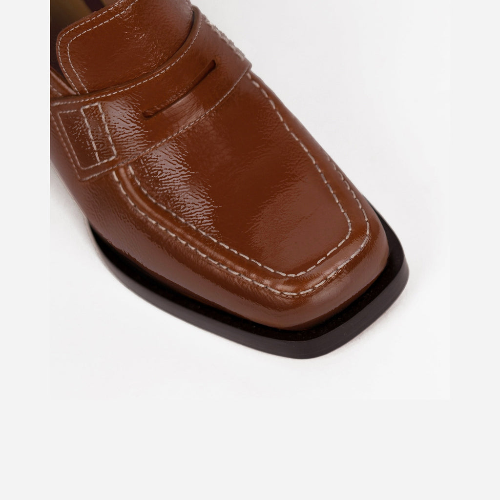 Close-up of brown loafer with a black sole on a white background