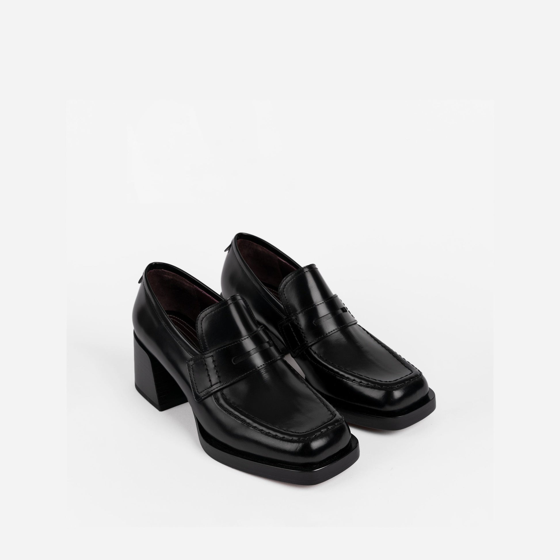 Pair of black loafers with a 2-inch block heel on a white background