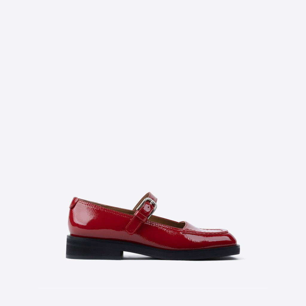 Red patent leather shoe with a strap on a white background