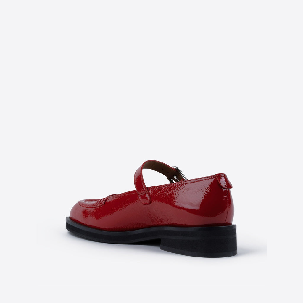 Red patent leather shoe with a black sole on a white background