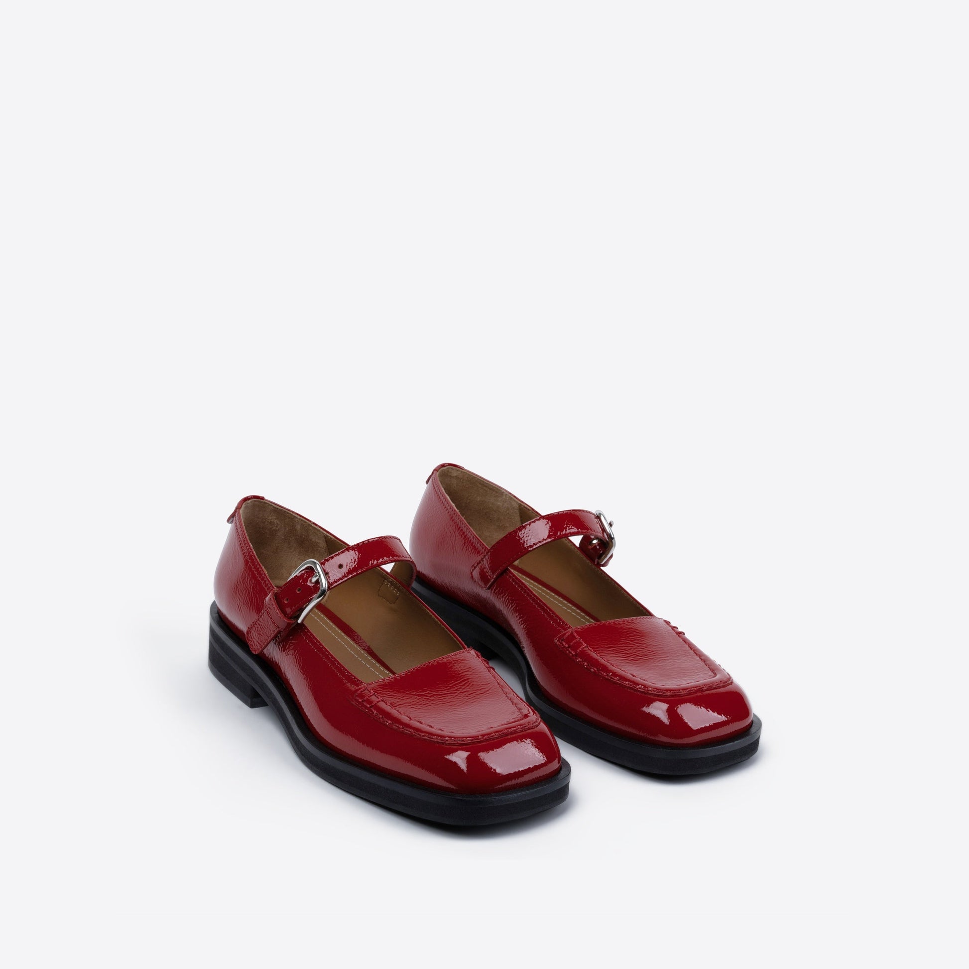 Pair of red patent leather shoes on a white background