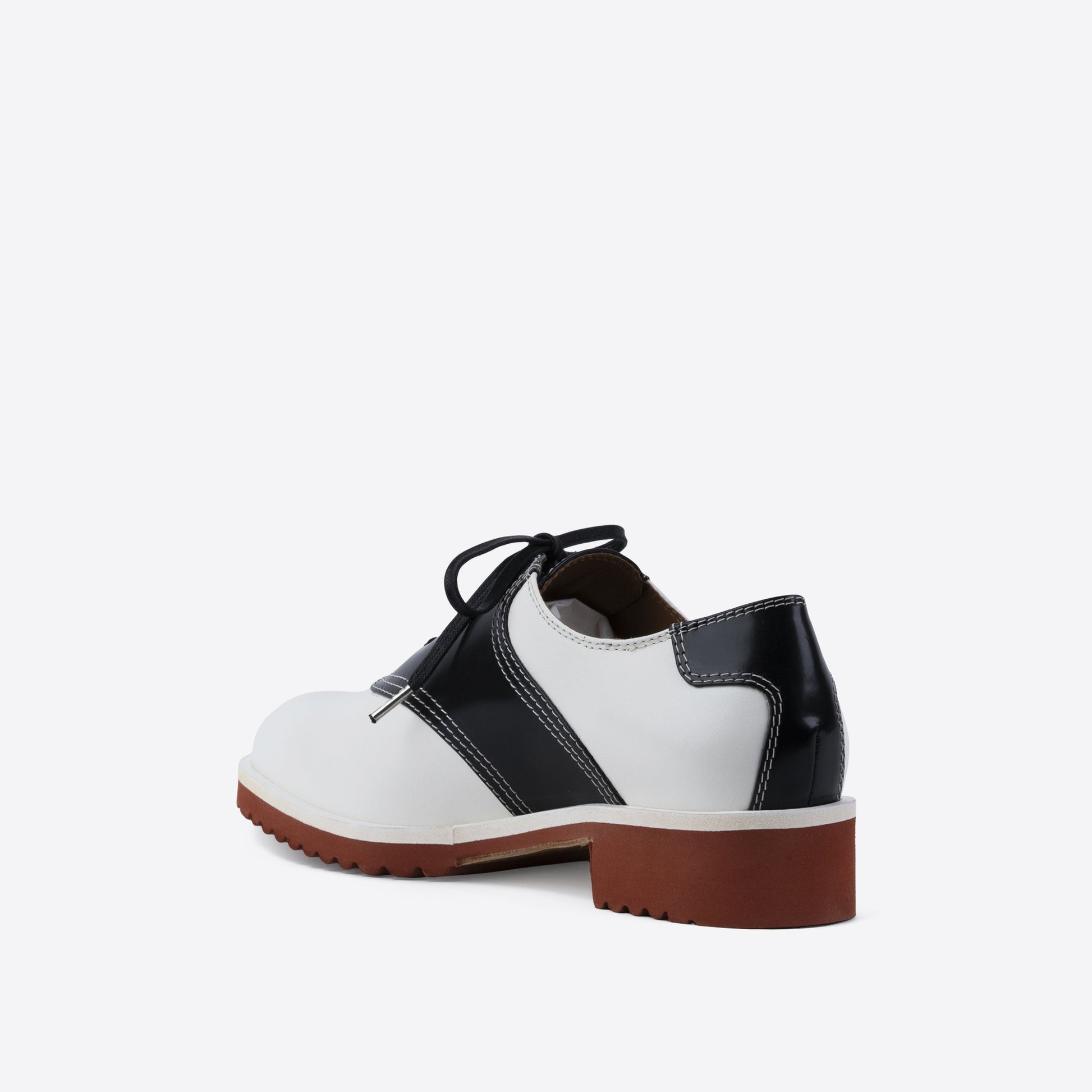 White and black leather shoe with black laces and a brown sole on a white background