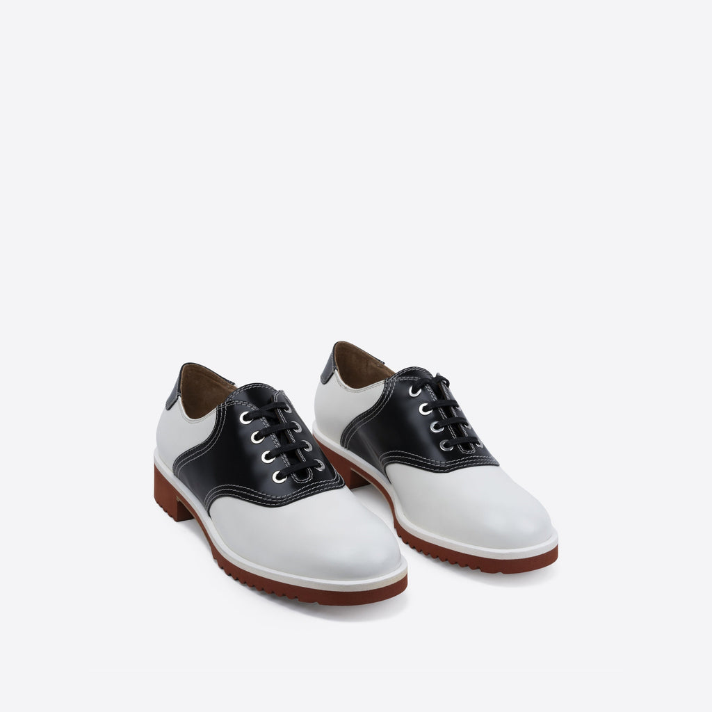 Pair of white and black leather shoes with black laces and a brown sole on a white background