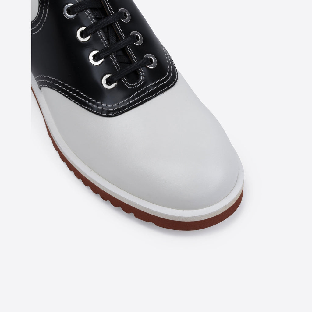 Black and white shoe with a brown sole on a light gray background