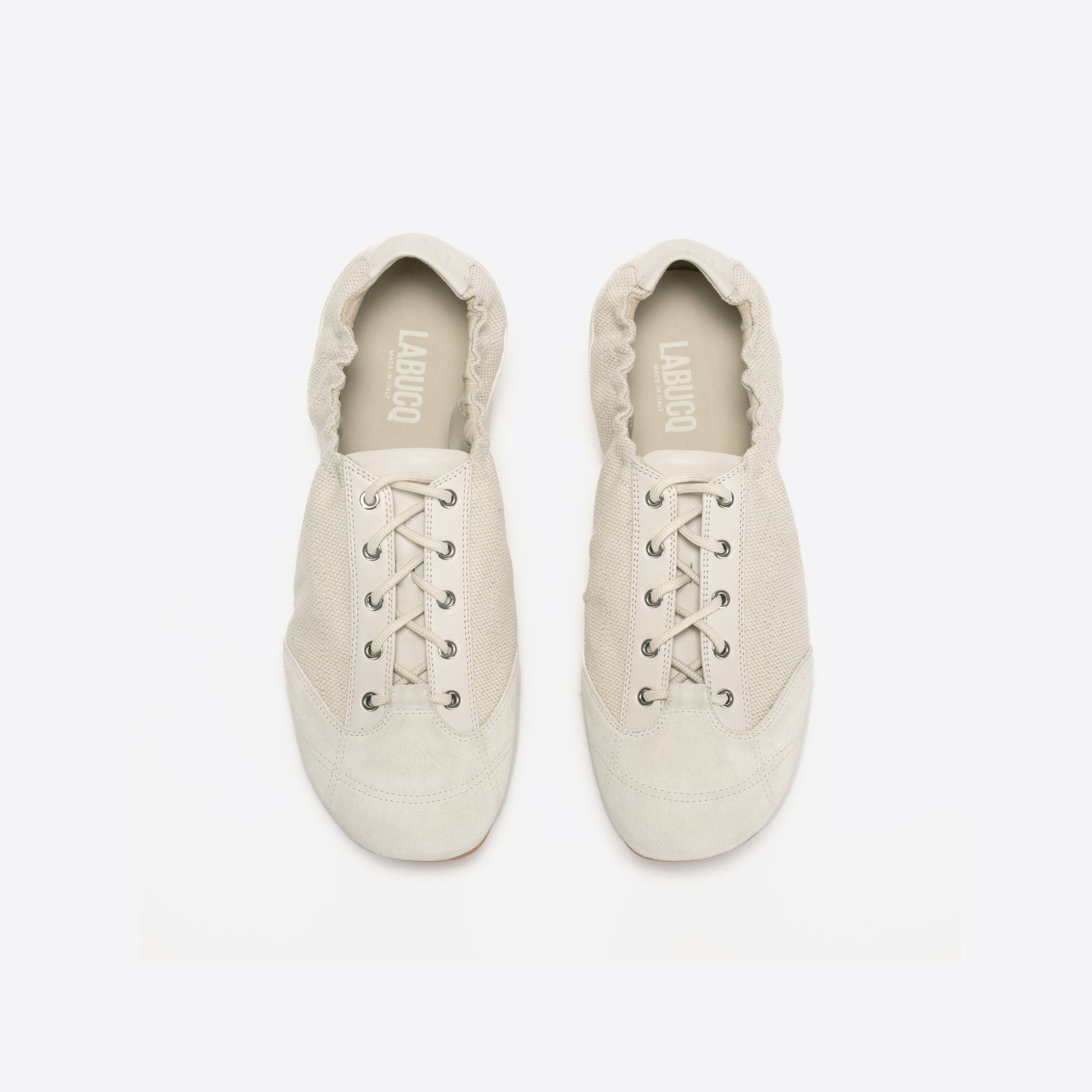 Pair of white shoes with lace-up design on a light gray background