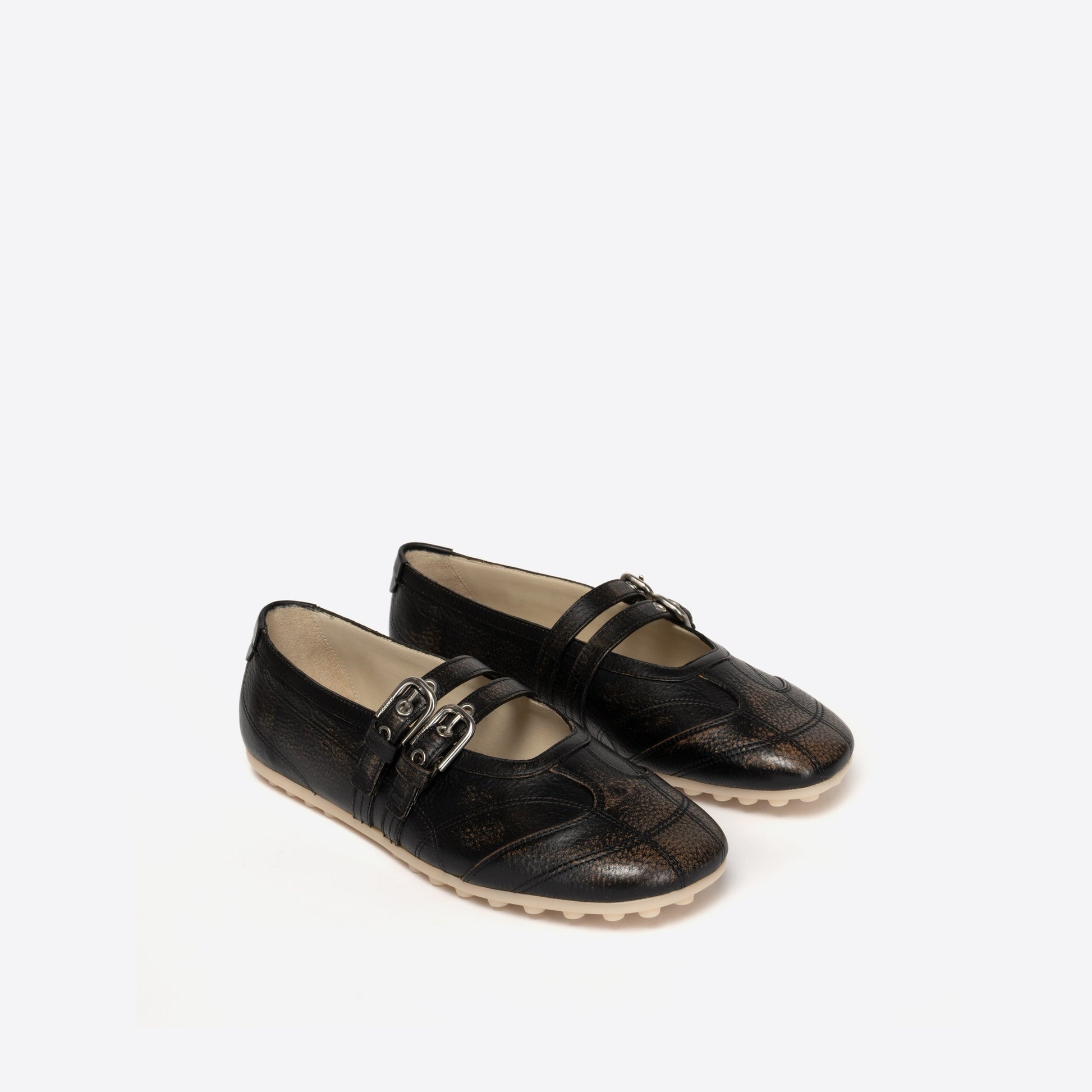 Pair of black Mary Janes with a beige sole on a white background
