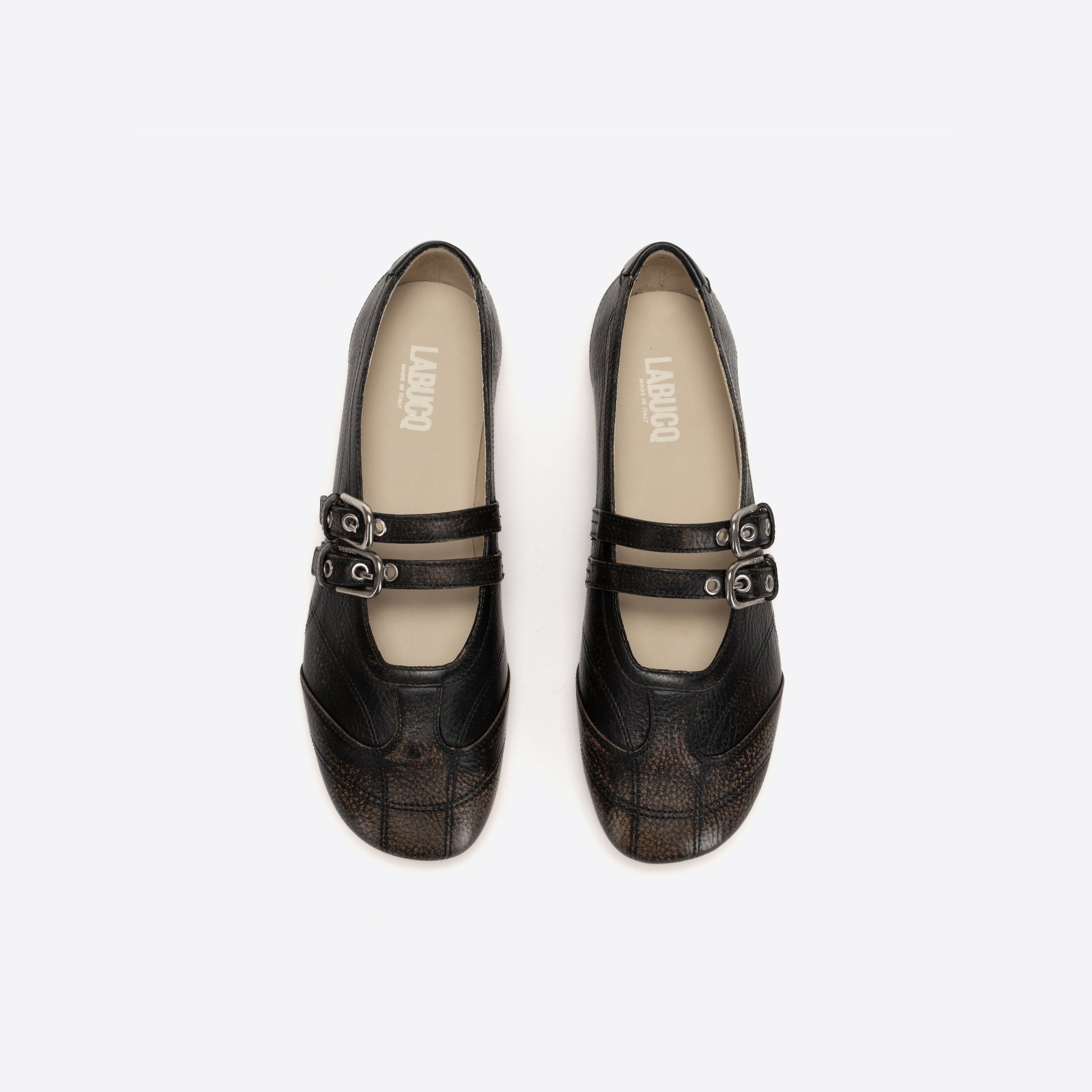 Pair of black Mary Janes with buckles on a white background
