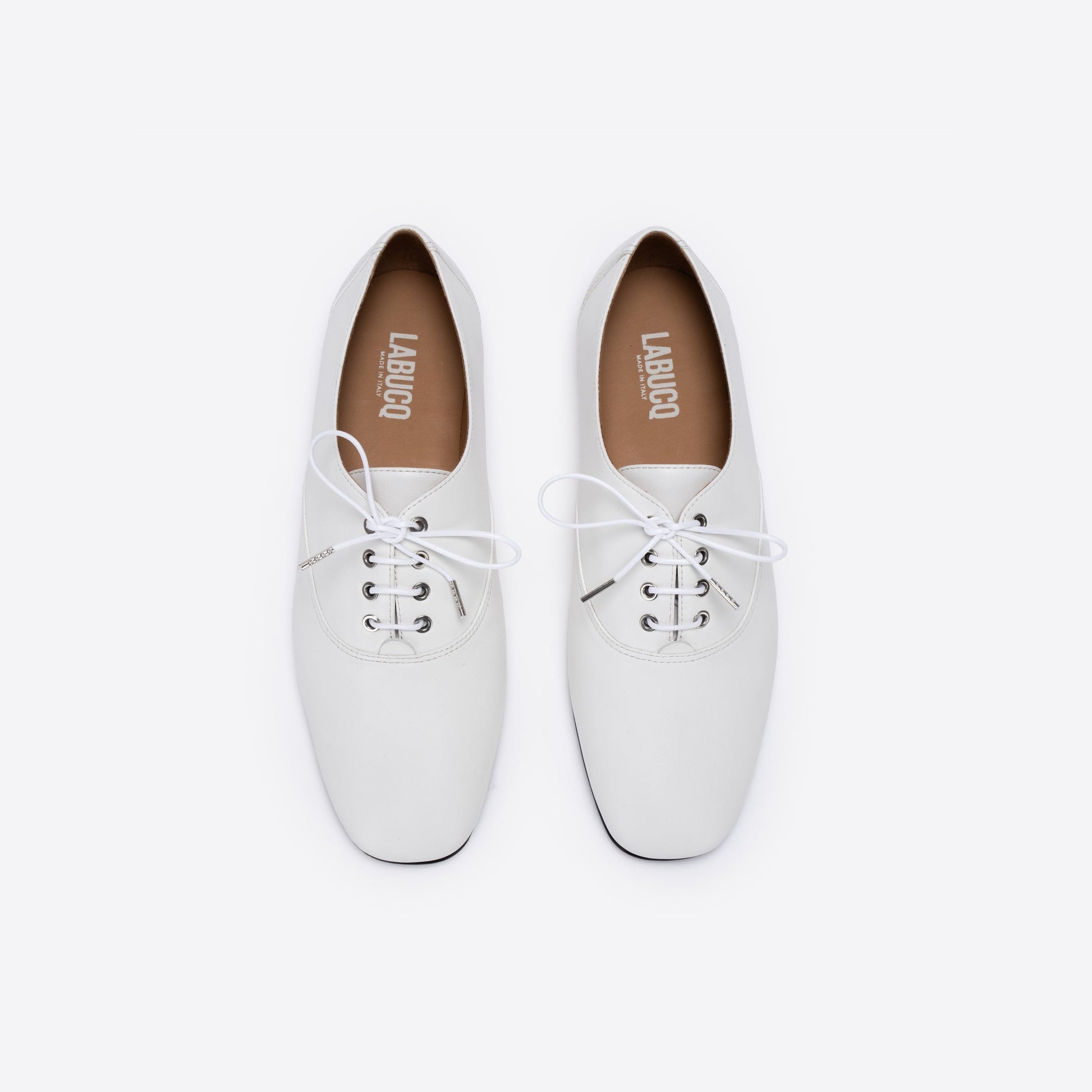 White leather shoes with 'Labucq' branding on a white background